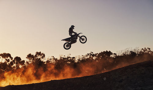 Low angle view of man riding bicycle against sky during sunset