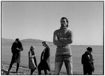 People standing at beach against clear sky