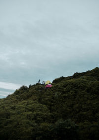 Low angle view of people on mountain against sky