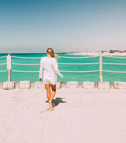 Full length of woman standing on beach against clear sky