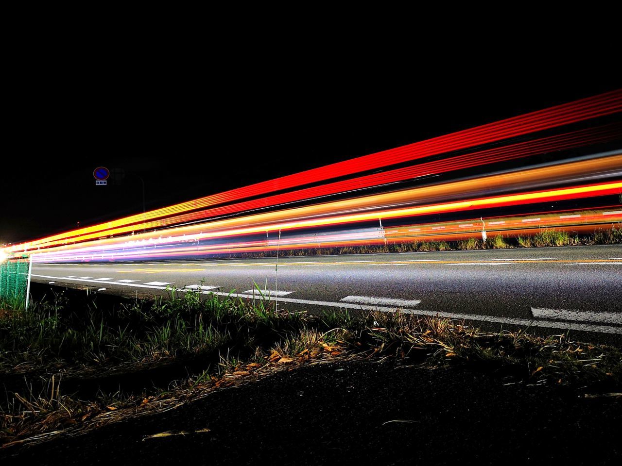 LIGHT TRAILS ON ROAD IN CITY AGAINST SKY AT NIGHT