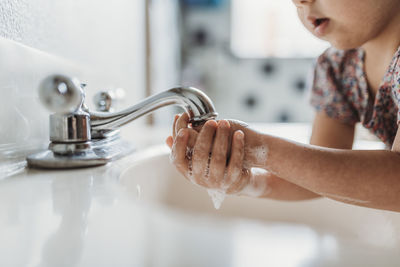 Close up view of young child washing hands with soap in sink