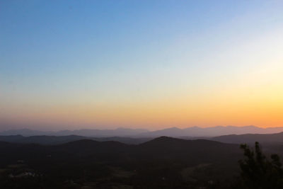 Scenic view of silhouette mountains against clear sky during sunset