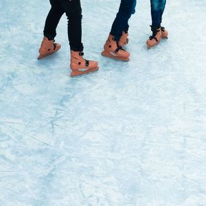 Low section of people ice-skating on rink