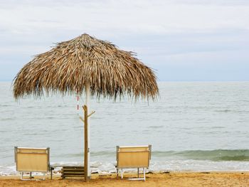 Deck chairs on beach against sky