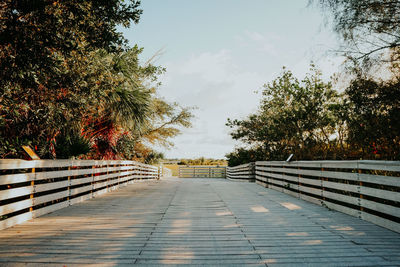 Footpath by railing against sky