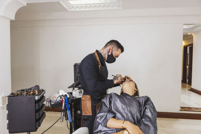 Side view of young woman using mobile phone while sitting at home