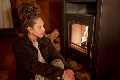 Relaxed woman sitting next to fireplace.