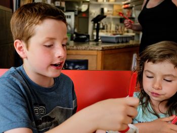 Smiling siblings eating food at restaurant