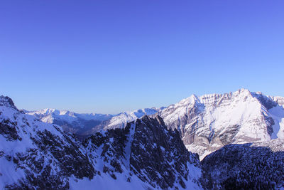 Scenic view of snowcapped mountains against clear blue sky