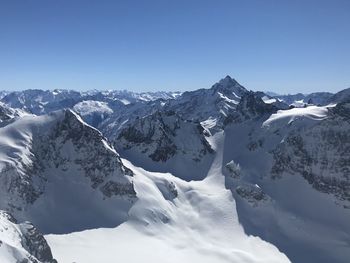 Scenic view of snowcapped mountains against clear blue sky