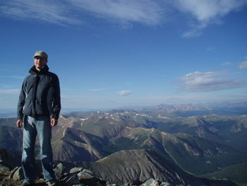 Full length of young man standing on mountain against sky