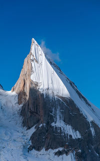 Snow covered mountain against blue sky