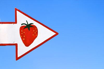 Low angle view of road sign against clear blue sky