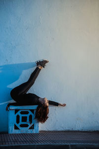 Full length of woman lying down by wall outdoors