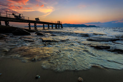 Two motorcycles on pier at sunset