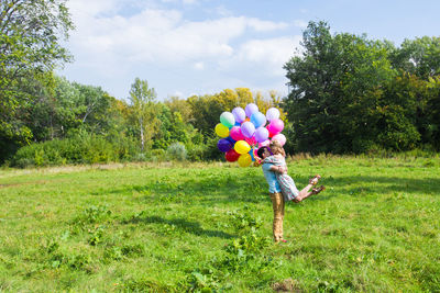 Rear view of boy playing with balloons on field