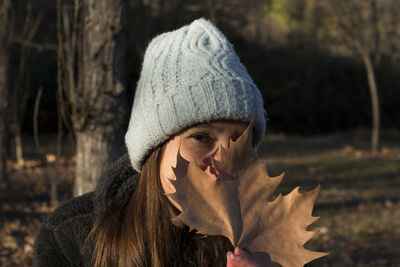 Close-up portrait of young woman holding leaf