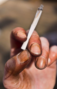 Close-up of hand holding cigarette