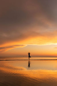 Meditation woman practicing tree yoga pose on the beach at sunset. copy space.