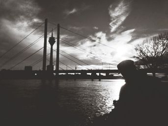 Bridge over river against cloudy sky