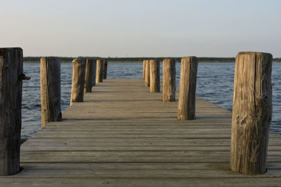 Wooden pier on sea against clear sky