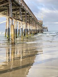 Wooden posts on beach against sky