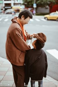 Full length of father with son on street in city