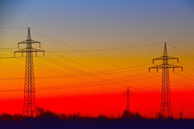 Low angle view of silhouette electricity pylon against sky during sunset