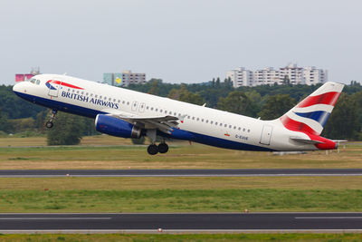 Airplane flying over airport runway against sky