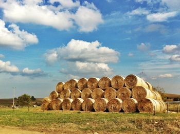 Stack of hay bales on field against sky