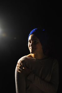 Portrait of mid adult woman against black background