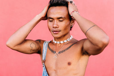 Shirtless young man with head in hands against colored background