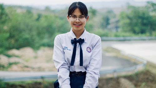 Portrait of smiling young woman wearing eyeglasses standing outdoors