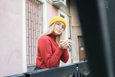 Portrait of woman wearing hat standing against wall