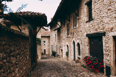 Street with facades of old stone buildings in perouges, france, red roses. high quality photo