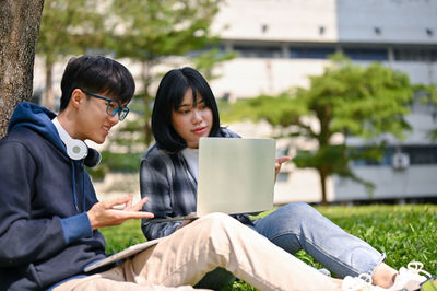 Young woman using laptop while sitting on bench