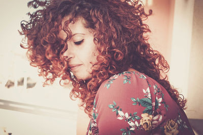 Side view of woman with curly hair sitting at home