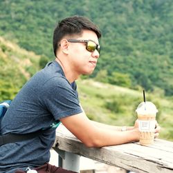 Young man looking away while sitting outdoors