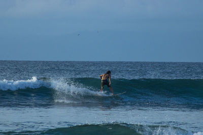 Man surfing in sea against sky