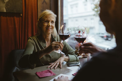 Smiling woman toasting wine glass with man on date at restaurant