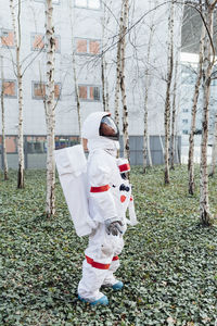 Young female astronaut looking up while standing in garden