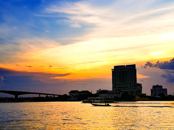 Sea by city against sky during sunset