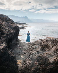 Pretty woman in a nice dress watching the horizon at the sea