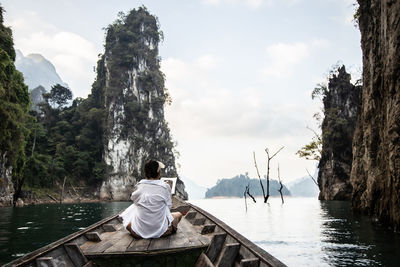 An asian woman in a white shirt sits in front of a boat  in thailand. amazing thailand.