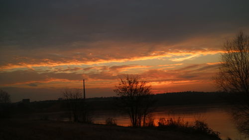 Silhouette of factory against orange sky