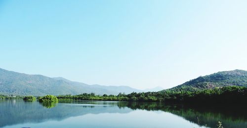 Scenic view of lake and mountains against clear blue sky