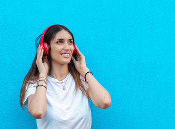 Portrait of smiling young woman standing against blue wall