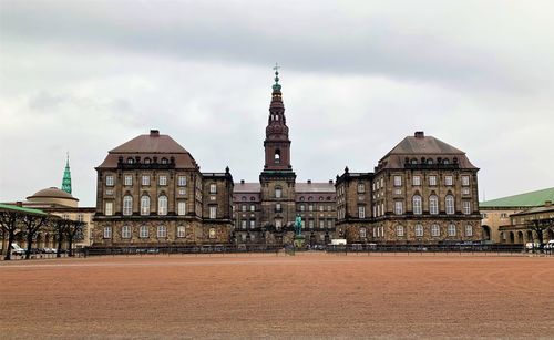 Buildings in city against cloudy sky