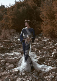 Full length portrait of young woman standing on rock